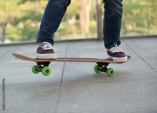 closeup of skateboarder legs riding skateboard outdoor © lzf