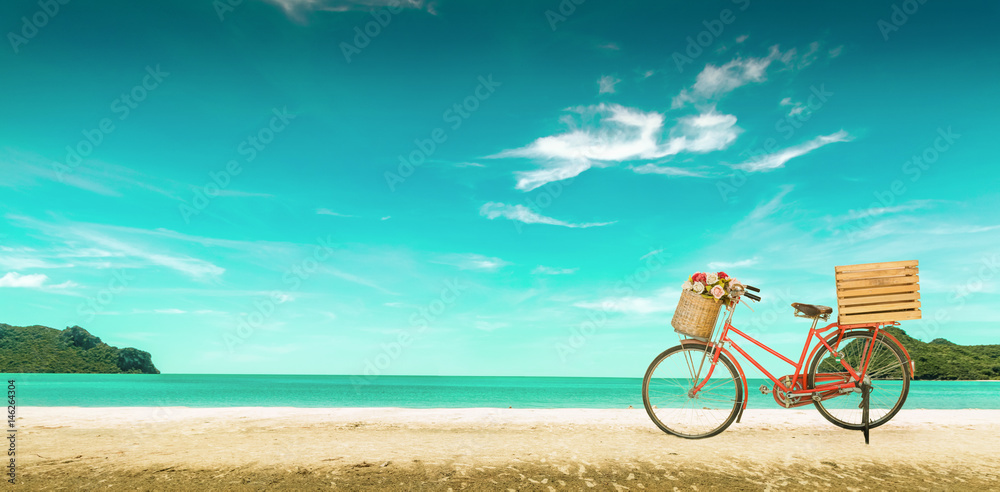 Fototapeta premium Red vintage bicycle on white sand beach over blue sea and clear blue sky background, spring or summer holiday vacation concept,vintage style.