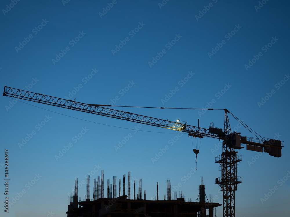 silhouette of construction crane on sunset sky background