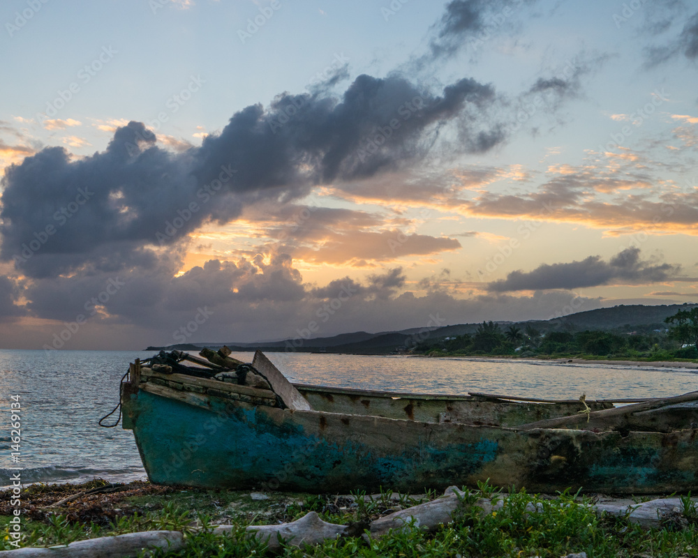 Washed up fishing boat on beach at sunrise Jamaica