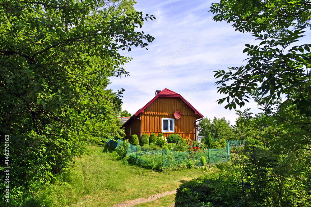 Brązowy, drewniany domek wśród zieleni