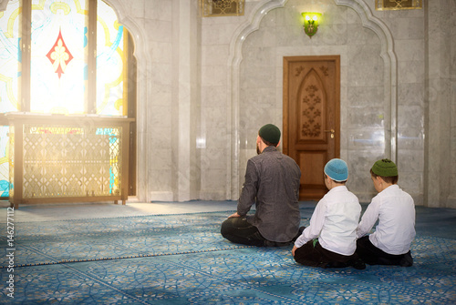 Father and sons pray in the mosque