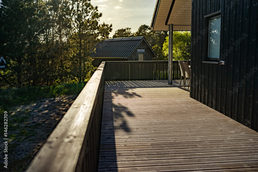 Fototapeta premium Holzterrasse im Ferienhaus beim Sonnenuntergang