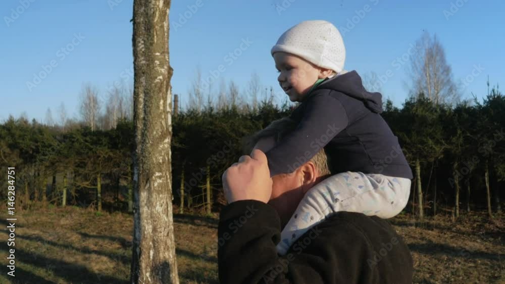 The kid sits on his grandfather's neck and they walk in the park at sunset. My granddaughter likes to ride a man. The kid sits on his grandfather's neck and they walk in the park at sunset. My granddaughter likes to ride a man.