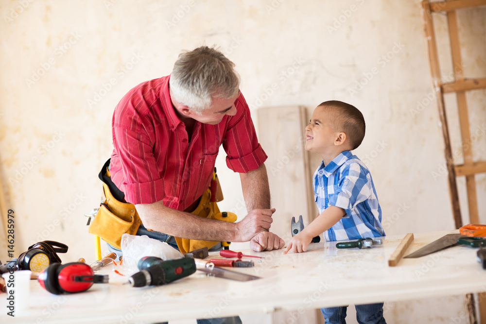 Smiling grandfather and grandson working in workshop Smiling grandfather and grandson working in workshop