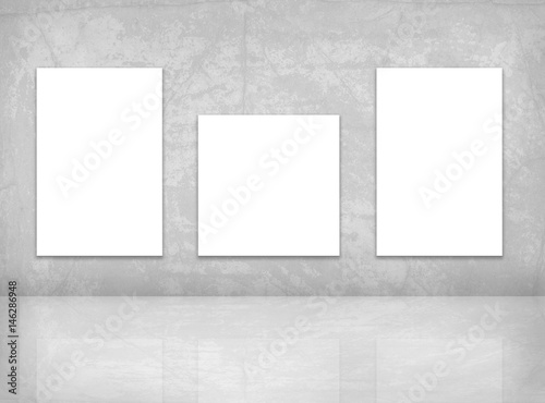 Mock up posters template. Three blank canvas on the grey wall.
