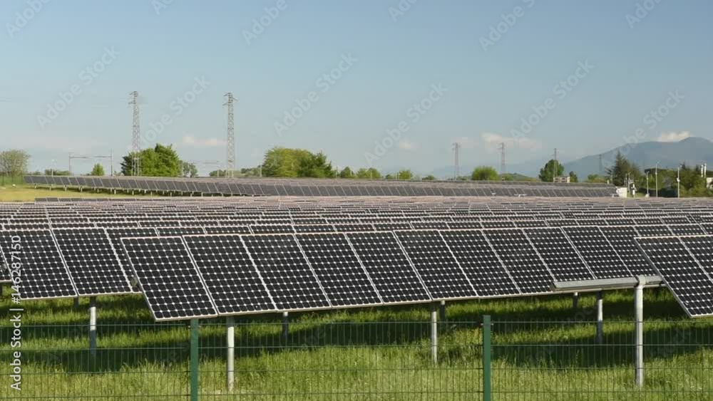 Solar panels multitude on green field and clear blue sky, panning left to right Solar panels multitude on green field and clear blue sky, panning left to right