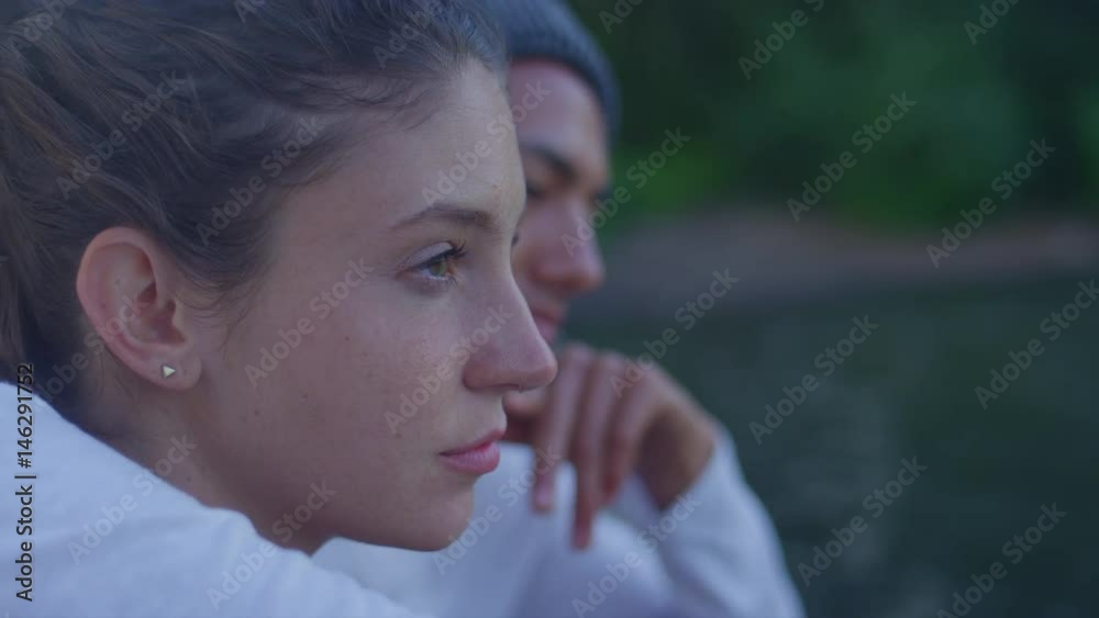 A young couple sitting on a dock together, close up on girl's face A young couple sitting on a dock together, close up on girl's face