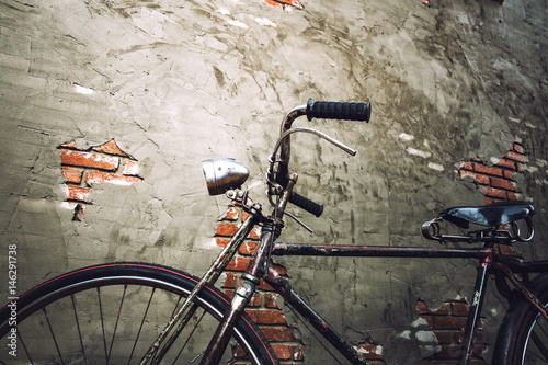 bicycle parked by an weathering brick wall