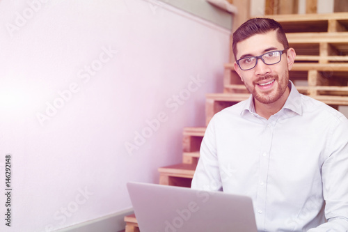 Portrait of young man sitting at the stairs in office