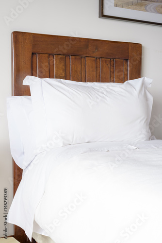 Wooden bed with pillows and linen white sheets