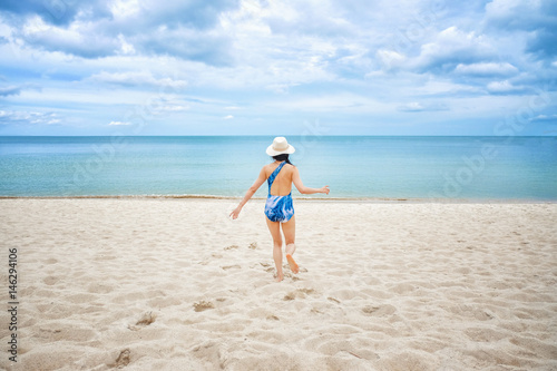 Young happy woman running on the beach