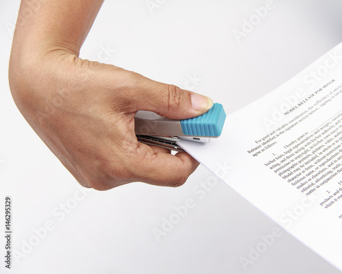 Close-up of woman's hand stapling paper on white background