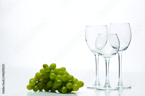Wine glasses and a bunch of grapes on a white background