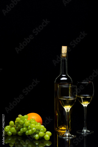 Glasses for wine, grapes and oranges on a black background