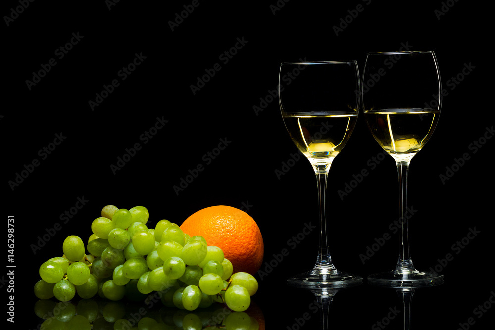 Glasses for wine, grapes and oranges on a black background