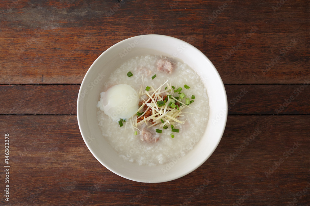 Pork rice porridge with egg on the wooden table. Top view, flat lay style. Pork rice porridge with egg on the wooden table. Top view, flat lay style.