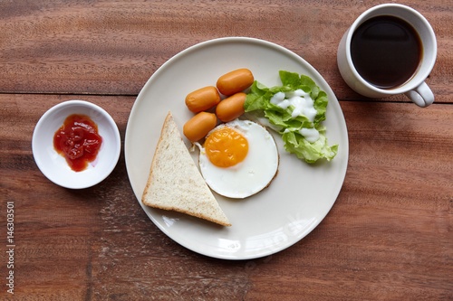 Quick and easy breakfast, fried eggs with sausages, toast and salad.