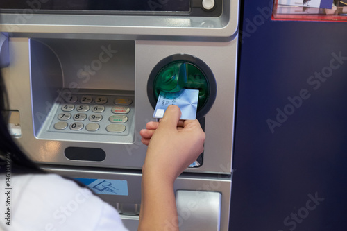 Asian woman inserting card to ATM Machine to withdraw cash. Financial transaction concept.