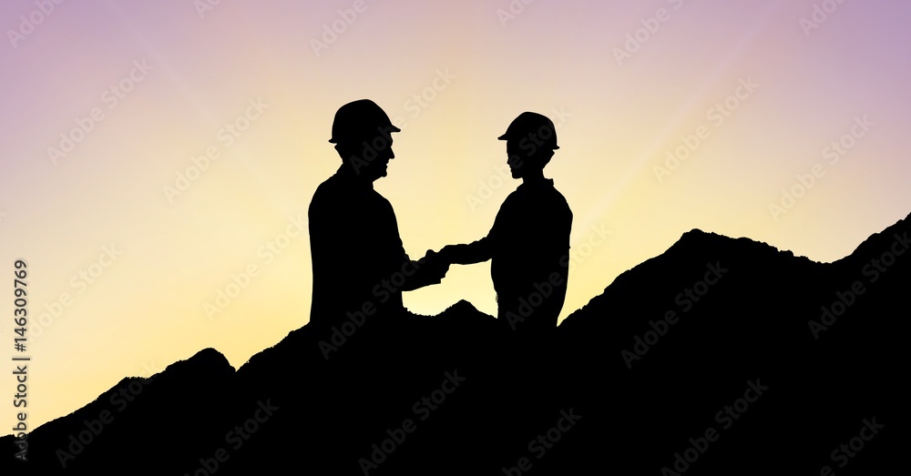 Silhouette architects shaking hands on mountains during sunset