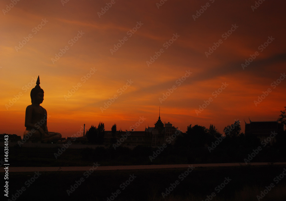 Silhouette of Big Buddha statue on sun set with foreground fishing tool.