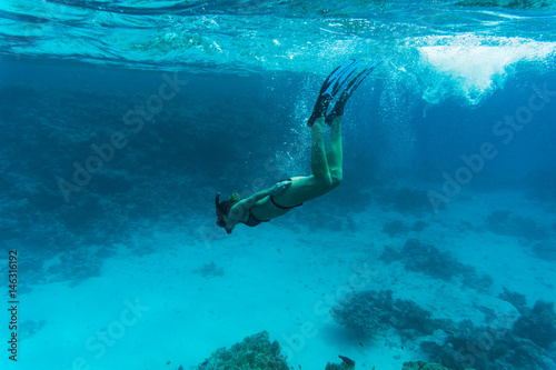 Young lady snorkeling over coral reef in the tropical sea under water