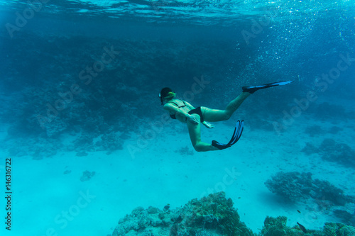Young lady snorkeling over coral reef in the tropical sea under water