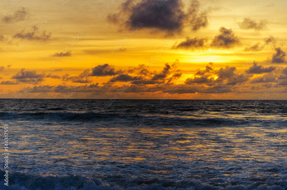  Silhouettes of a wave and clouds on a color sky during sunset. Evening on a tropical beach.