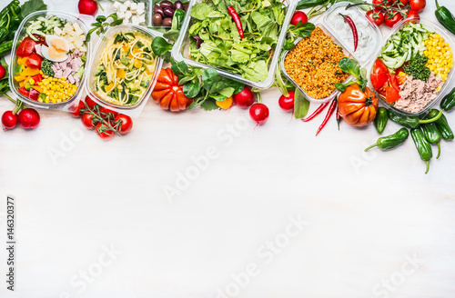 Healthy food concept. Variety of vegetables salad bowls in  plastic package on white wooden background, top view, border. Salad bar. Take away Diet lunch ideas