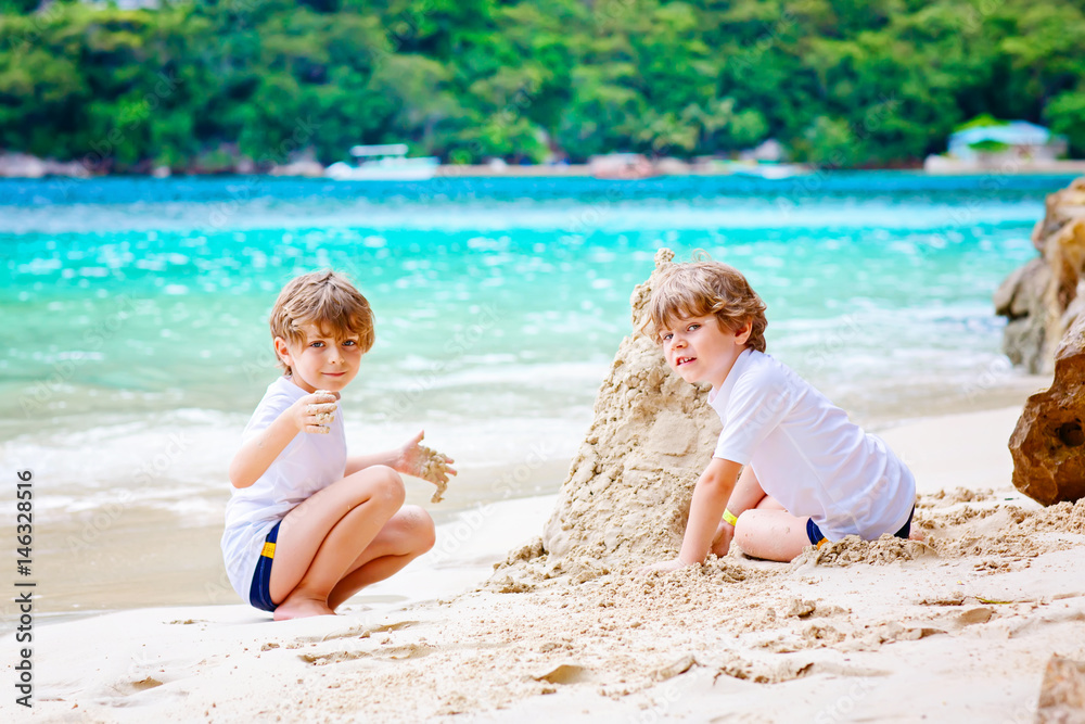 Two kid boys building sand castle on tropical beach Two kid boys building sand castle on tropical beach
