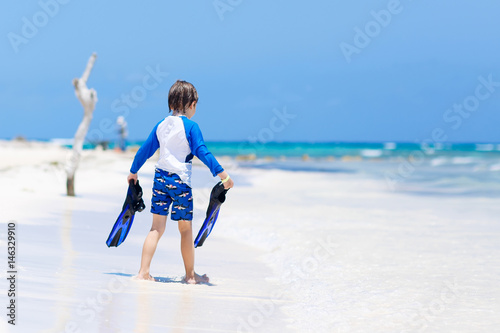 little blond kid boy having fun on tropical beach of Maldives