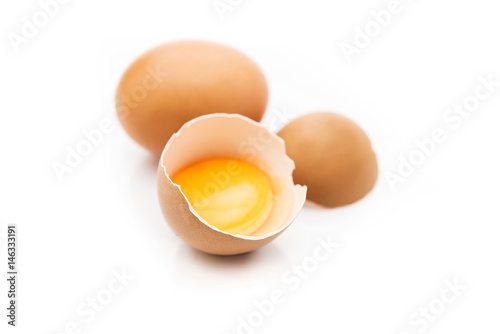 Huevo moreno roto con fondo blanco y yema dentro