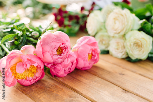 holidays flowers and floral arrangement concept - close-up on beautiful flowers of pink peony and white roses, freshness of natural plant, bouquets on wooden table, selective focus