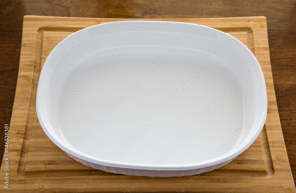 Empty White Casserole Dish on Wood Cutting Board Stock Photo | Adobe Stock