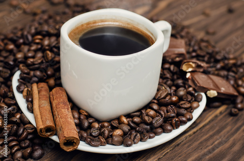 Coffee cup with beans, chocolate and cinamon on a wooden table