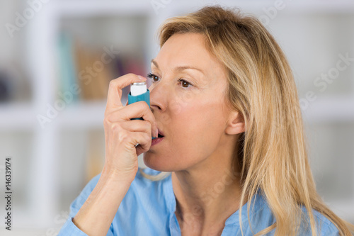 close-up of woman using the asthma inhaler in her living-room