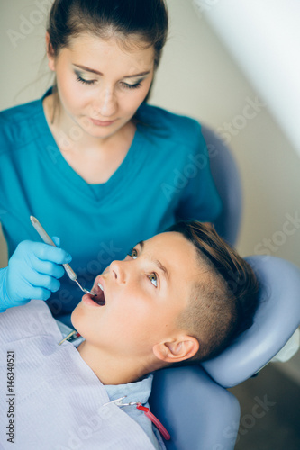 Hansome teenager boy having his teeth examined by a dentist