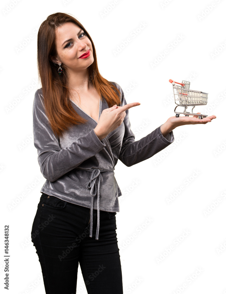 Beautiful young girl holding a supermarket cart toy Beautiful young girl holding a supermarket cart toy