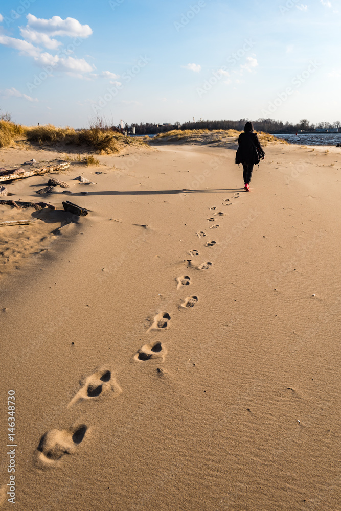 anonymous person walking on a sand at windy beach anonymous person walking on a sand at windy beach