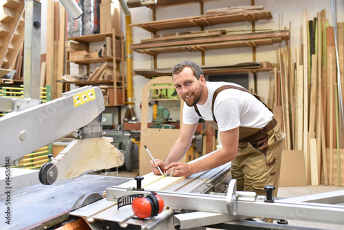 Tischler arbeitet an einer Säge in einer Schreinerei // Carpentry working on a saw in a carpenter's workshop photo