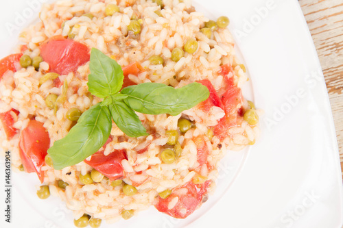 Risotto with tomato and pea on a wooden background 