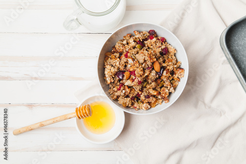 Morning granola with dried fruits, honey, milk and berries on white wooden background. Top view with copy space