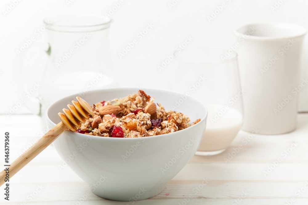 Morning granola with dried fruits, honey, milk and berries on white wooden background. Side view with copy space Morning granola with dried fruits, honey, milk and berries on white wooden background. Side view with copy space