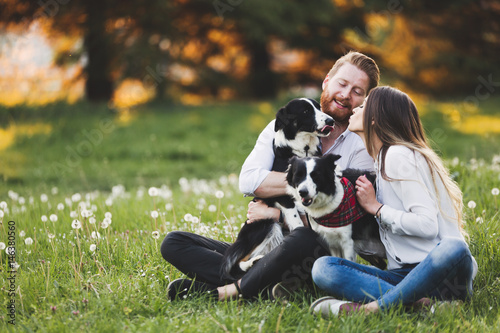 Canvas Print Beautiful couple cuddling and walking dogs outdoors