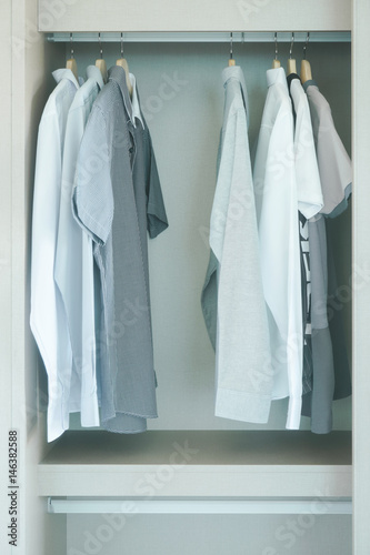 Men's cloths hanging in white wardrobe