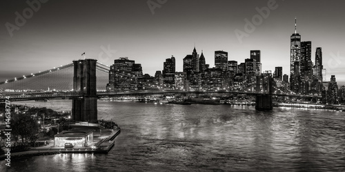 Black & White elevated view of the Brooklyn Bridge and Lower Manhattan skyscrapers at dusk. Skyline of the Financial District with East River. New York City