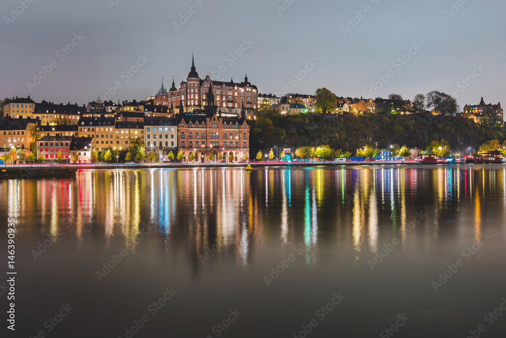 Stockholm city lights and night view of Sodermalm district buildings reflected in the water. Evening Stockholm cityscape with illumination, Riddarfjarden marina and Soder Malarstrand embankment.