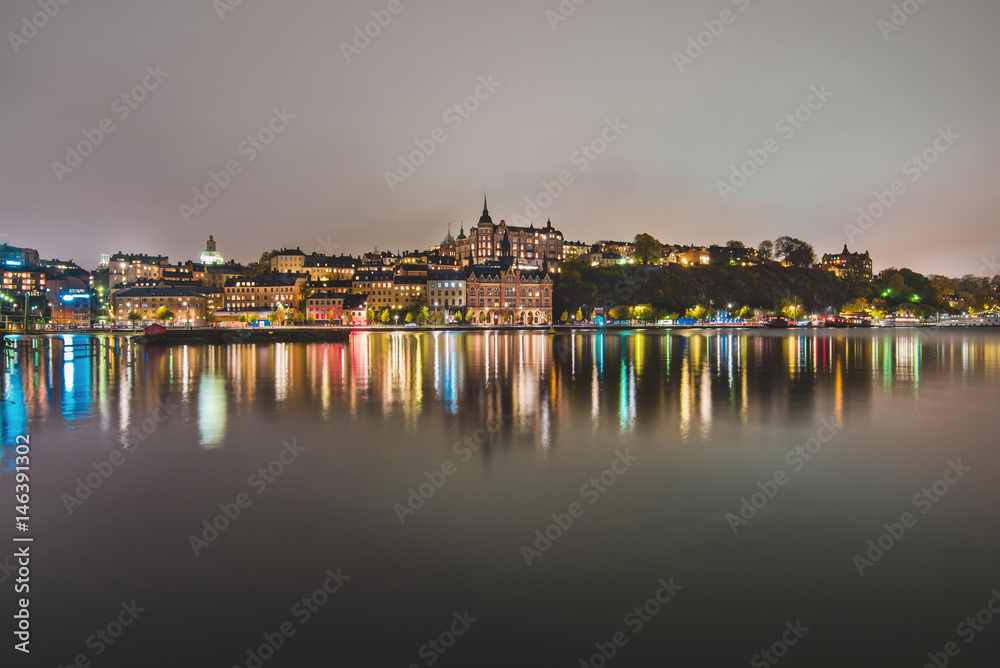 Stockholm city lights and night view of Sodermalm district buildings reflected in the water. Evening Stockholm cityscape with illumination, Riddarfjarden marina and Soder Malarstrand embankment.