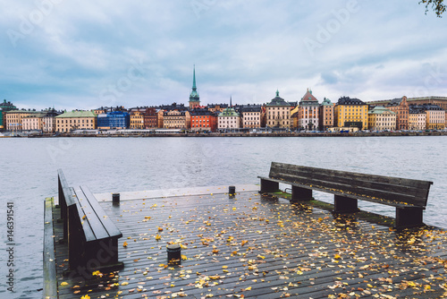 Wide angle view of Stockholm Old Town and Saltsjon bay from Skeppsholm island sea pier. Autumn Stockholm skyline with Gamla Stan, Old German Church and wooden jetty on Skeppsholmen. photo