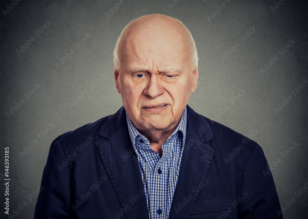 Obraz premium Elderly sad skeptical man looking down